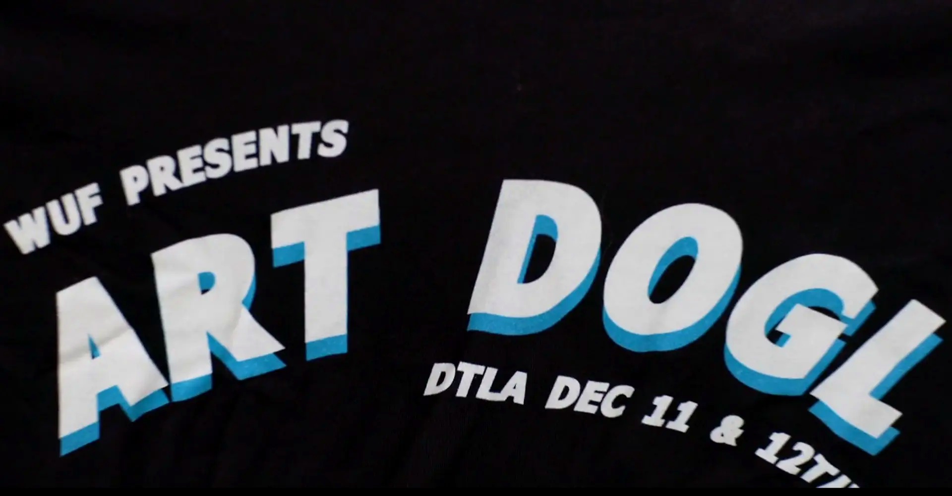 Close-up of a WUF Presents Art DOGL DTLA tee printed in white and blue