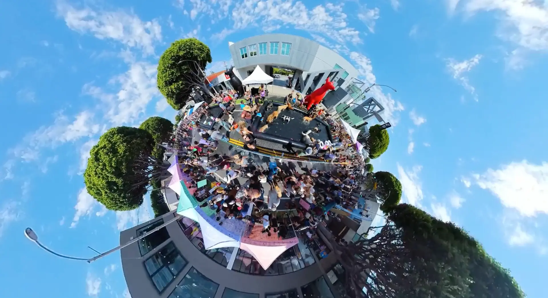 Tiny-planet view of the festival street packed with crowds, tents and food stands