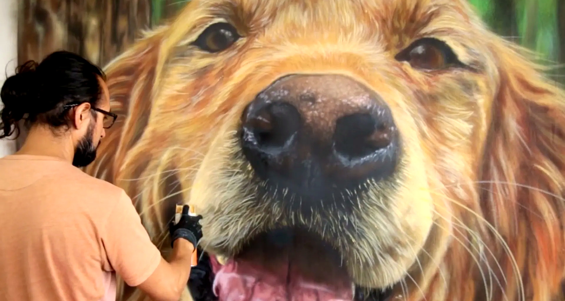 Artist airbrushing a monumental golden retriever mural in front of a crowd