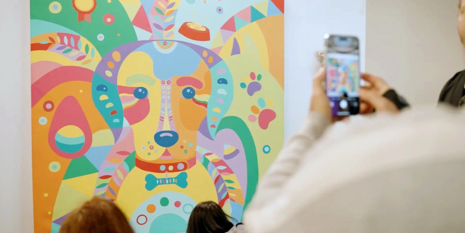 Visitors photographing a large geometric, pastel painting of a dog