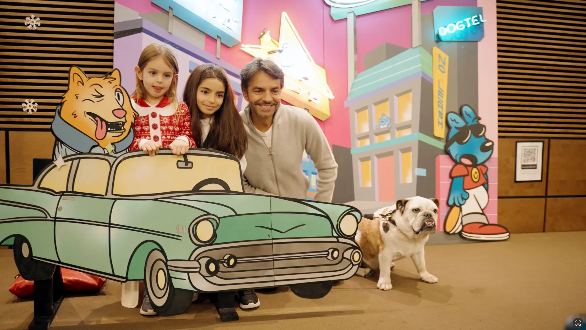 A family and their bulldog posing in a cartoon convertible at the DOGTEL set